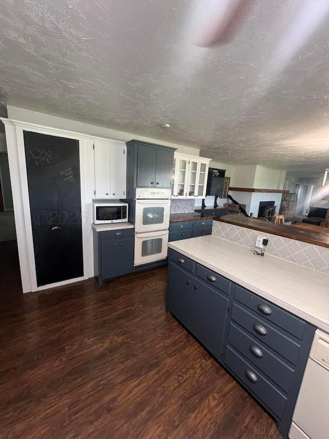 kitchen with dishwasher, double oven, a textured ceiling, white cabinets, and dark hardwood / wood-style flooring