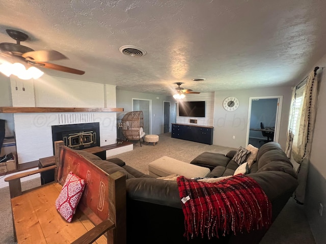 carpeted living room featuring ceiling fan and a textured ceiling