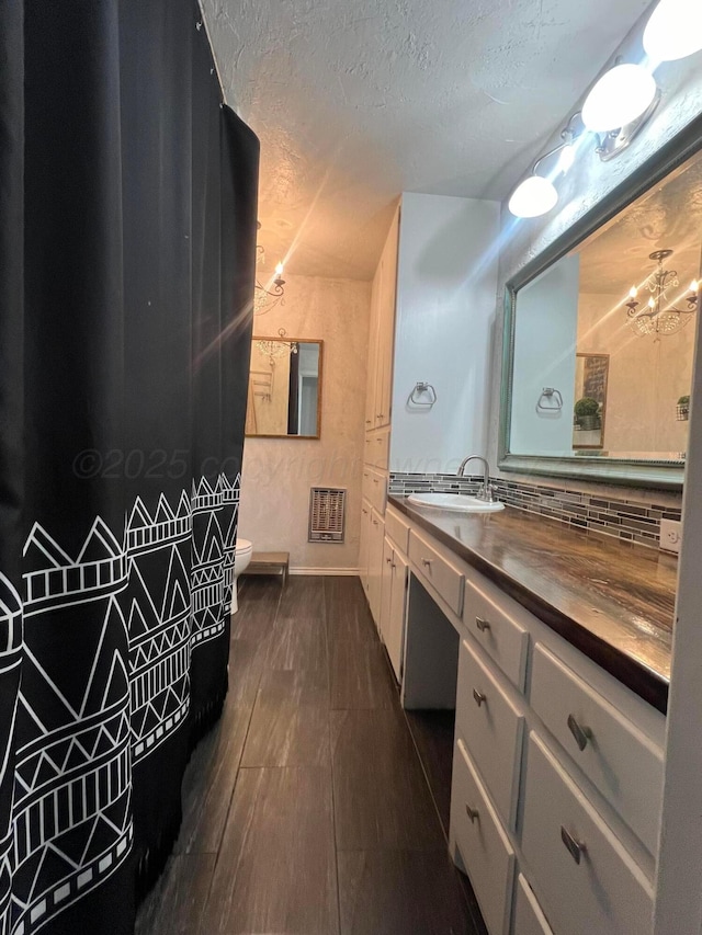 bathroom featuring tasteful backsplash, vanity, toilet, a textured ceiling, and an inviting chandelier