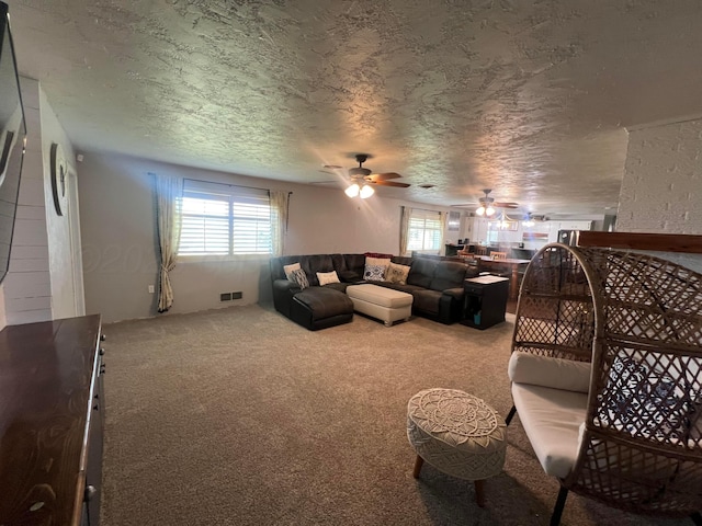 carpeted living room featuring ceiling fan and a textured ceiling