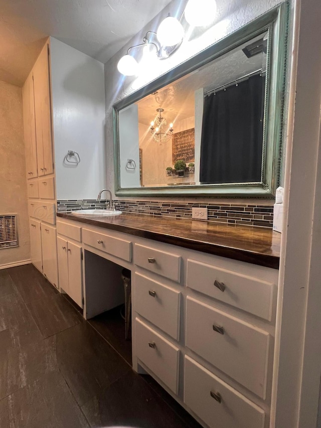 bathroom featuring heating unit, decorative backsplash, hardwood / wood-style flooring, vanity, and a notable chandelier