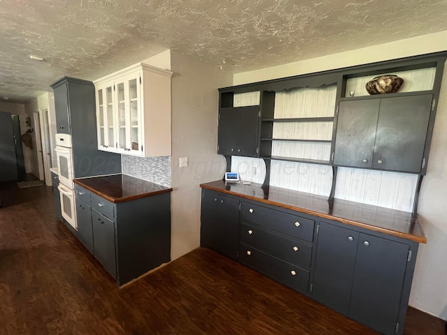 kitchen featuring white cabinetry, dark wood-type flooring, a textured ceiling, and decorative backsplash