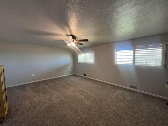 carpeted empty room with ceiling fan and a textured ceiling