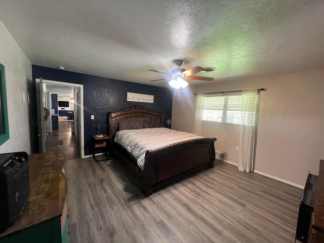 bedroom with hardwood / wood-style floors, a textured ceiling, and ceiling fan