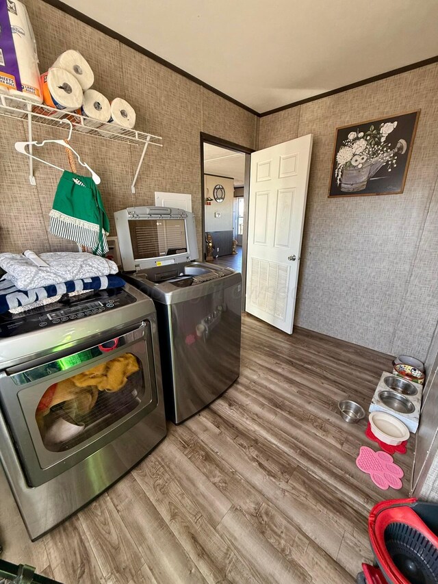 420 N 18th St, Memphis, TX 79245 - clothes washing area featuring laundry area, wood finished floors, washer and dryer, ornamental molding, and wallpapered walls