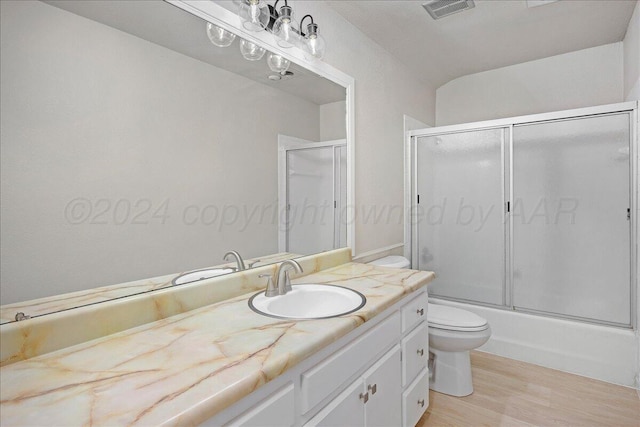 full bathroom featuring hardwood / wood-style flooring, vanity, toilet, and bath / shower combo with glass door