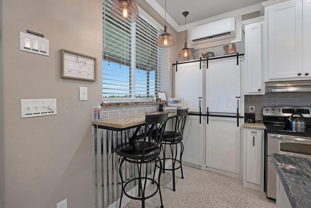 kitchen with white cabinets, a wall mounted AC, tasteful backsplash, and stainless steel range with electric stovetop