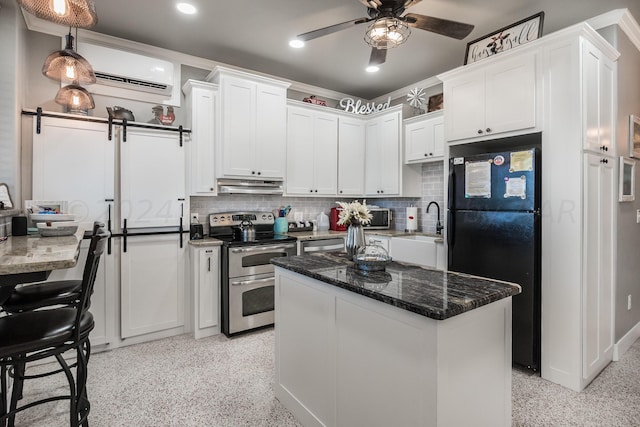 kitchen featuring stainless steel electric range oven, a wall mounted air conditioner, a barn door, black fridge, and white cabinets