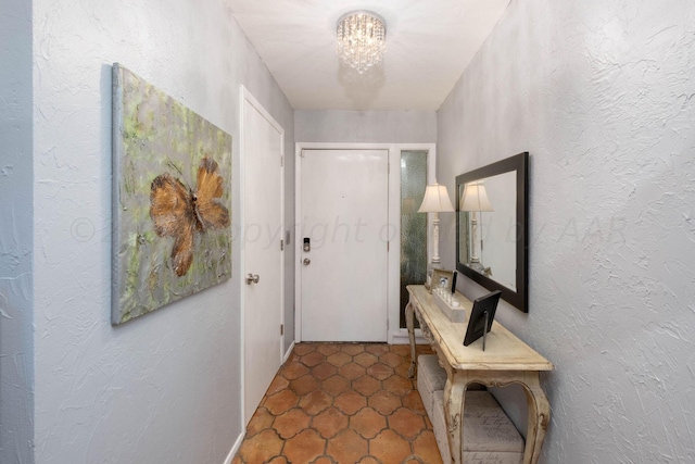 doorway with dark tile patterned flooring and an inviting chandelier