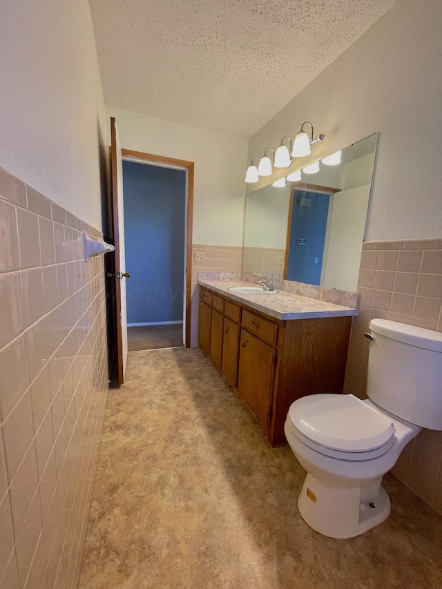 bathroom featuring tile walls, vanity, a textured ceiling, and toilet