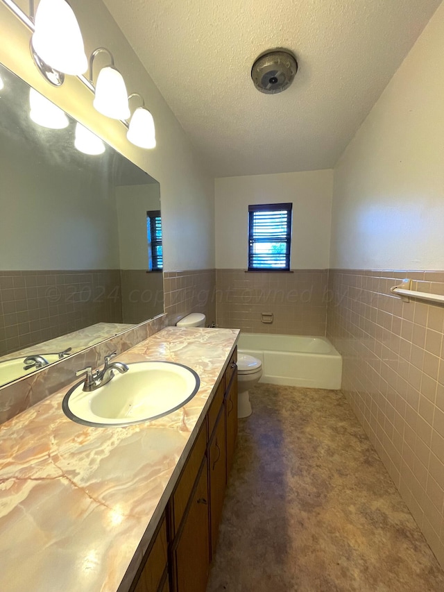 bathroom featuring vanity, tile walls, a textured ceiling, and a bathing tub