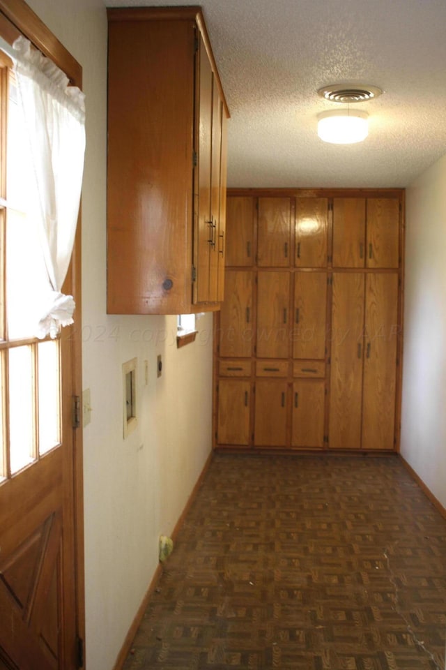 hallway featuring a textured ceiling and dark parquet flooring