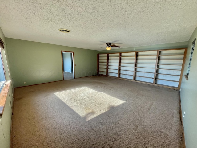 interior space featuring a textured ceiling, light colored carpet, and ceiling fan