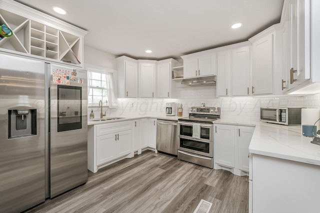 1033 Bowie St, Amarillo, TX 79102 - kitchen with appliances with stainless steel finishes, under cabinet range hood, a sink, open shelves, and white cabinetry