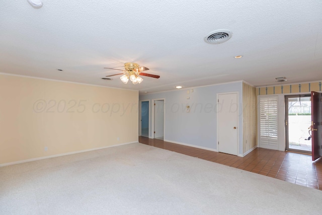 spare room with carpet, visible vents, ceiling fan, and a textured ceiling