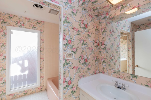 full bath featuring wallpapered walls, visible vents, a bath, and vanity