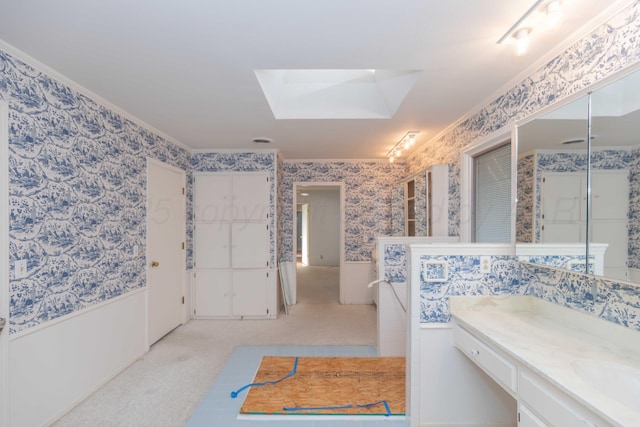 bathroom with crown molding, a skylight, vanity, and wallpapered walls