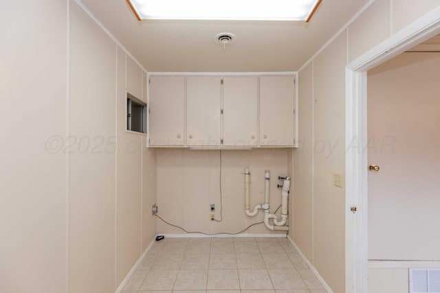 clothes washing area with visible vents, light tile patterned floors, and cabinet space