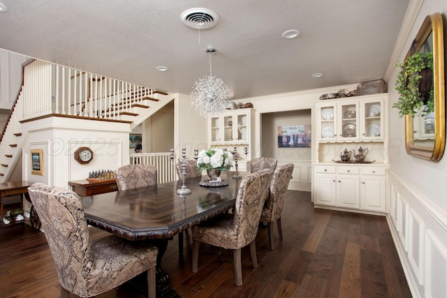 4214 Roxton Dr, Amarillo, TX 79109 - dining area featuring a chandelier, stairway, dark wood finished floors, a decorative wall, and ornamental molding