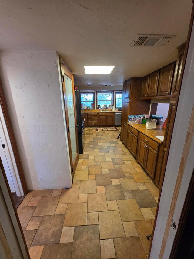 830 Burnett St, Miami, TX 79059 - kitchen featuring light countertops, freestanding refrigerator, dishwasher, stone finish floor, and visible vents