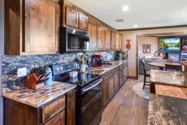 kitchen featuring visible vents, backsplash, wood finished floors, dark stone counters, and double oven range