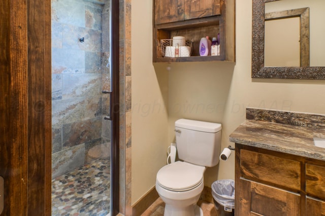 bathroom with toilet, a stall shower, and vanity