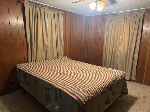 bedroom featuring carpet floors, ceiling fan, and wooden walls