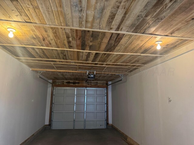 garage featuring a garage door opener, wood ceiling, and baseboards