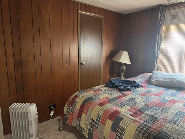 bedroom featuring wood walls, radiator heating unit, and carpet