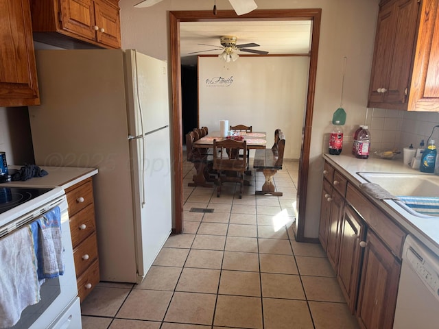 kitchen with brown cabinets, light countertops, backsplash, light tile patterned flooring, and white appliances