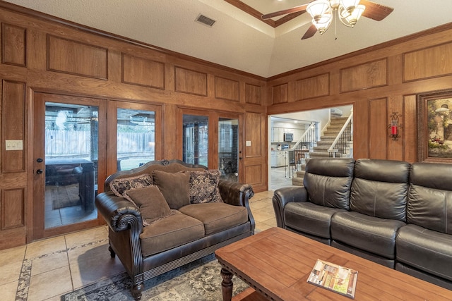 tiled living room featuring wood walls, ceiling fan, a textured ceiling, high vaulted ceiling, and crown molding