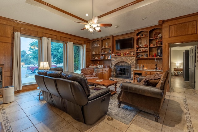 living room with built in shelves, a fireplace, a textured ceiling, wooden walls, and ceiling fan