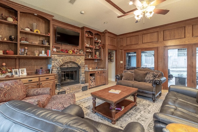 living room with a textured ceiling, a fireplace, wood walls, and ceiling fan