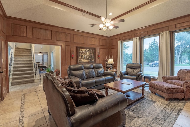 tiled living room featuring ceiling fan, a textured ceiling, crown molding, wooden walls, and vaulted ceiling