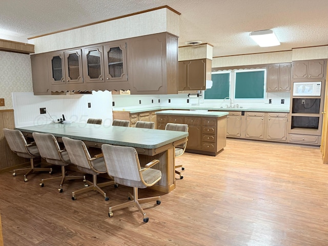 715 Ave P, Sunray, TX 79086 - kitchen with wallpapered walls, a textured ceiling, white microwave, light wood finished floors, and a warming drawer