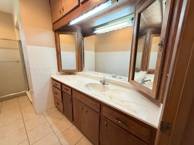 715 Ave P, Sunray, TX 79086 - full bathroom featuring double vanity, tile patterned flooring, a wainscoted wall, a shower stall, and tile walls