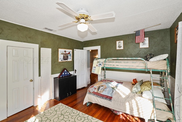 bedroom with a textured ceiling, dark hardwood / wood-style floors, and ceiling fan