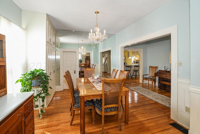 dining room with a chandelier, a textured ceiling, and light wood-type flooring