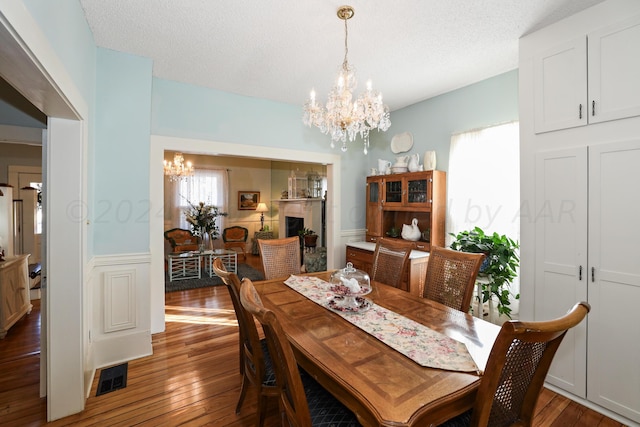 dining room featuring a textured ceiling, dark hardwood / wood-style flooring, plenty of natural light, and a notable chandelier