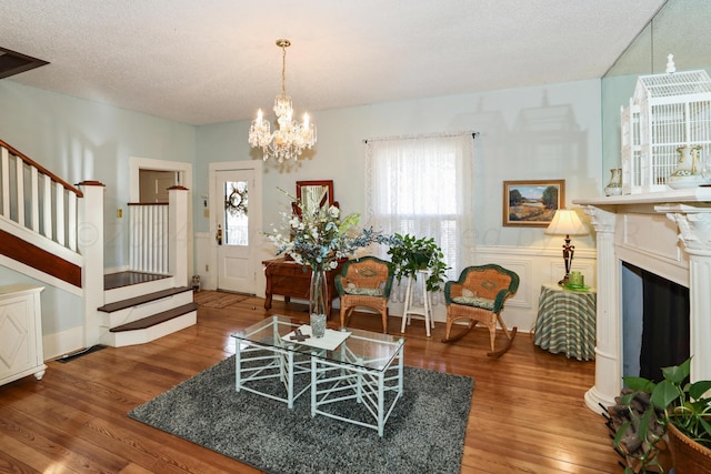 living room with hardwood / wood-style floors, a textured ceiling, an inviting chandelier, and a healthy amount of sunlight