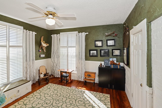 sitting room with ceiling fan, dark hardwood / wood-style flooring, and a textured ceiling