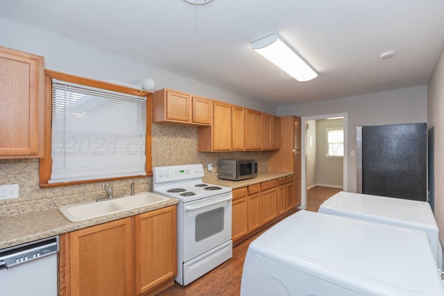 kitchen featuring refrigerator, white electric range oven, dishwashing machine, sink, and independent washer and dryer