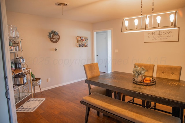 dining space with wood finished floors, visible vents, and baseboards
