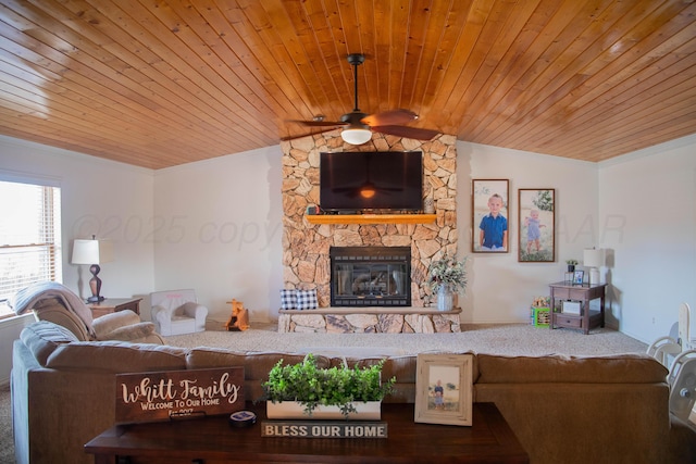 living room featuring vaulted ceiling, ceiling fan, wooden ceiling, a stone fireplace, and ornamental molding