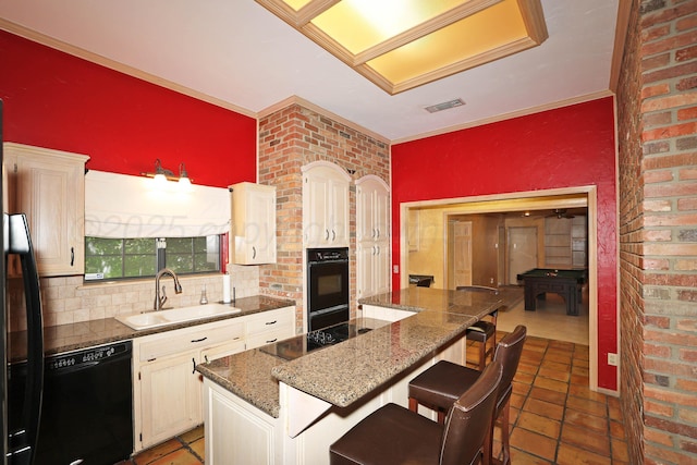 2604 Hawthorne Dr, Amarillo, TX 79109 - kitchen featuring black appliances, a sink, a kitchen bar, backsplash, and a center island