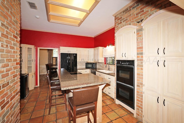 2604 Hawthorne Dr, Amarillo, TX 79109 - kitchen with black appliances, a center island, a sink, a breakfast bar, and light stone counters