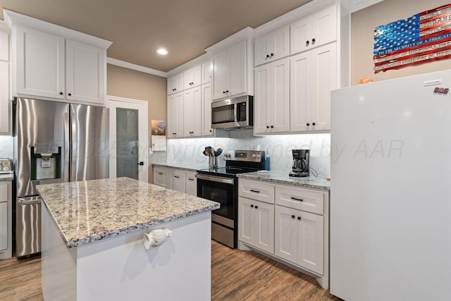 kitchen featuring appliances with stainless steel finishes, a center island, white cabinets, and light stone counters