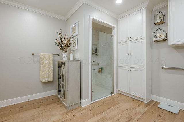 bathroom with wood-type flooring, a shower with door, and crown molding