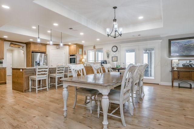 dining room with a raised ceiling, crown molding, light hardwood / wood-style floors, and a notable chandelier