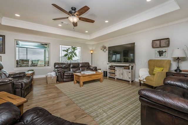 living room featuring hardwood / wood-style flooring, ceiling fan, a raised ceiling, and ornamental molding